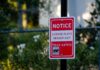 Red notice sign on a pole in a leafy suburban area