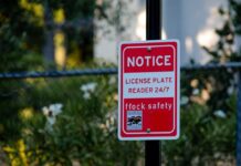 Red notice sign on a pole in a leafy suburban area