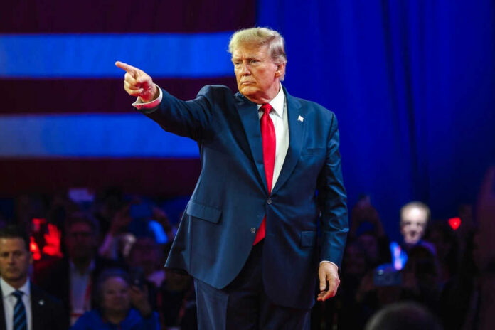 Person in suit pointing on stage with audience watching