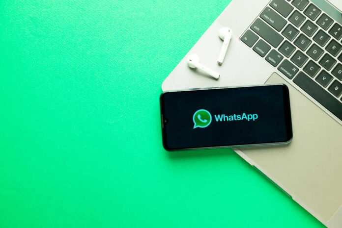 whatsapp730348928 Smartphone on laptop with WhatsApp displayed alongside earbuds
