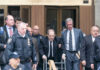 Man using walker surrounded by people in suits.
