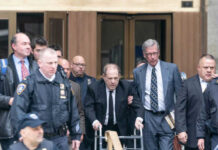 Man using walker surrounded by people in suits.