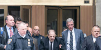 Man using walker surrounded by people in suits.