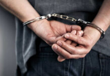 Person handcuffed with hands behind back.