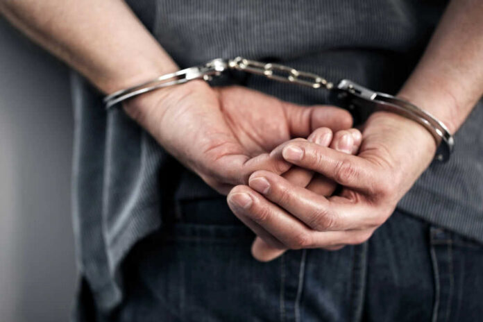 70908647 Person handcuffed with hands behind back.