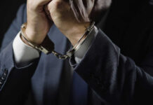Businessperson in suit with hands cuffed together