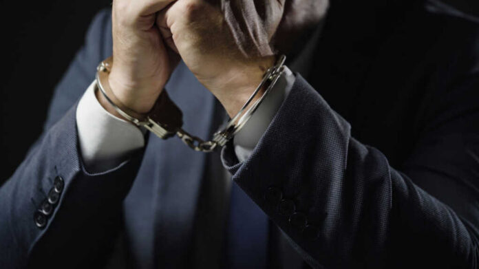 Businessperson in suit with hands cuffed together