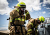 Firefighters in protective gear standing outside cloudy sky
