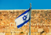 Israel Faces Surge in Terror Violence Israeli flag waving in front of an ancient stone wall