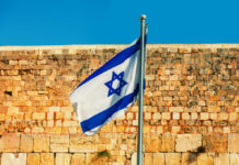 Israeli flag waving in front of an ancient stone wall