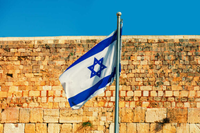 israeli-flag2465603939jpg Israeli flag waving in front of an ancient stone wall