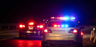 Police car with flashing lights parked on the roadside at night
