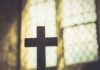 Same-Day Blazes Rattle Catholic France Silhouette of a wooden cross against a softly lit background
