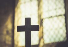 Same-Day Blazes Rattle Catholic France Silhouette of a wooden cross against a softly lit background