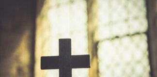 Silhouette of a wooden cross against a softly lit background