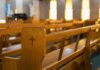 Wooden church pew with carved cross in a sunlit sanctuary