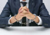 Agent’s ‘Expenses’: CIA Officer Allegedly Hid $40M in Gold A man in a suit with hands handcuffed together on a table
