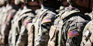 Soldiers in camouflage with American flag patches standing