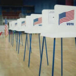 FBI Storms Fulton: What’s Hiding In Boxes? Voting booths lined up in a gymnasium.