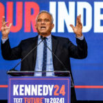Man speaking at podium with Kennedy24 campaign sign.