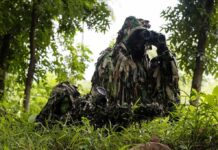 Leafy Stakeout Ignites Policing Debate camouflaged soldiers observing through binoculars in a forest