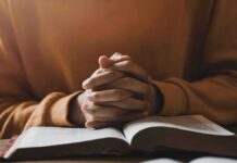 Hands clasped over an open book