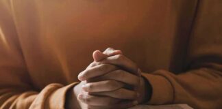 Hands clasped over an open book