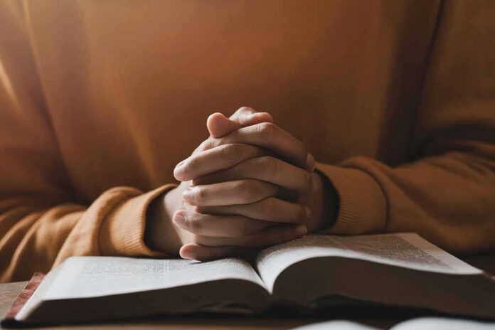 Hands clasped over an open book