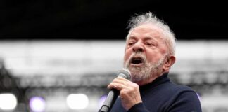 Elderly man speaking into a microphone on stage
