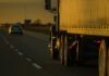 Semi-truck trailer driving on highway at sunset