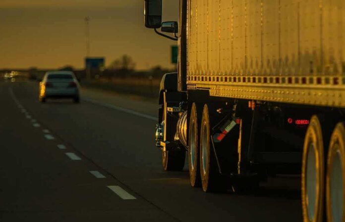 shutterstock_2289923583 Semi-truck trailer driving on highway at sunset