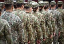 Soldiers in camouflage uniforms standing in formation from behind