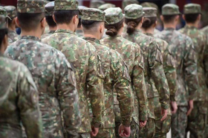 Soldiers in camouflage uniforms standing in formation from behind