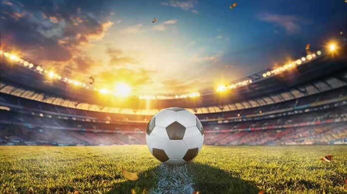 shutterstock_2447101709 Soccer ball on stadium field at sunset