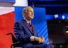Texas Lands Navy Megayard—At What Cost? A man in a blue suit sitting in a wheelchair on a conference stage