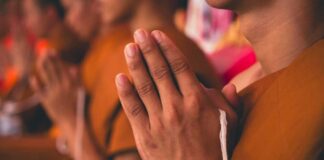 Monks with hands clasped in prayer during a ceremony