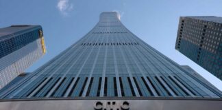 Curved glass skyscraper viewed from below against a clear blue sky