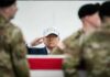 A man in a USA hat saluting during a military ceremony