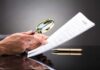 Hands holding magnifying glass over contract document
