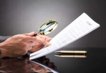 Hands holding magnifying glass over contract document