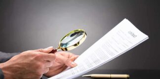 Hands holding magnifying glass over contract document