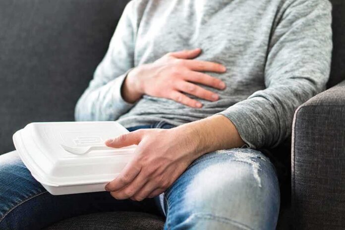 Person holding takeout container while touching stomach