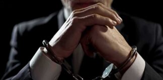 Businessperson in handcuffs with hands clasped
