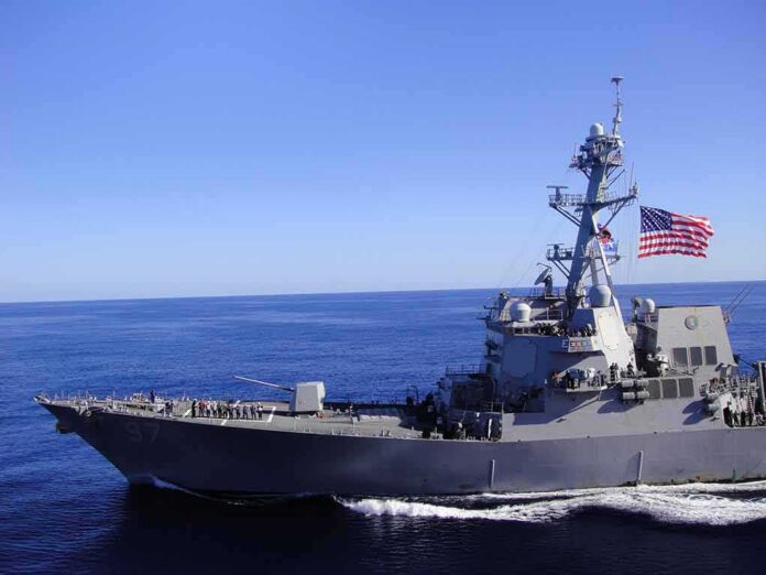 Naval destroyer sailing on open sea with flag flying