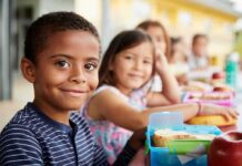 Free Meals Promise: Universal Credit Win—or Maze? Smiling boy at a lunch table with classmates