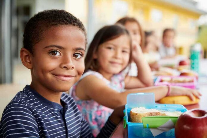 shutterstock_1177724560 Smiling boy at a lunch table with classmates