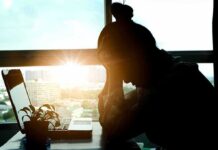 silhouetted person at a desk with head in hands