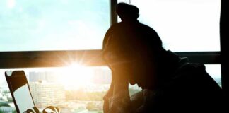 silhouetted person at a desk with head in hands