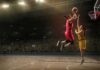 Two basketball players contest a layup under the hoop