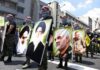 Protesters holding large portrait posters during a street march